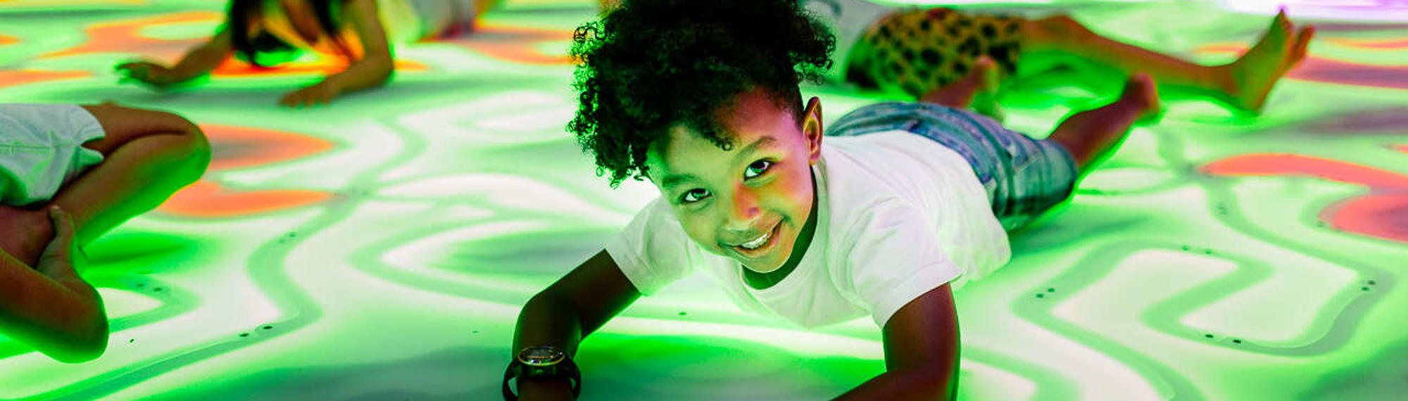 Four young guests enjoying themselves by "getting down" on the Frog Disco dancefloor, with one smiling to the camera.