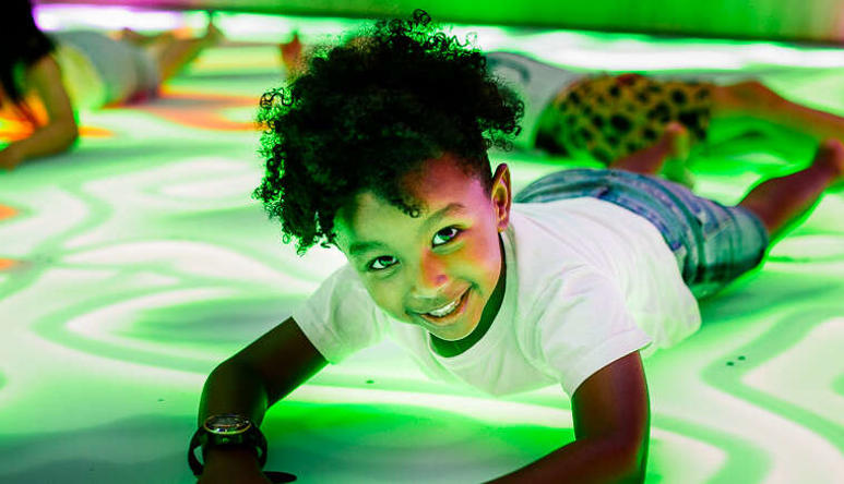 Four young guests enjoying themselves by "getting down" on the Frog Disco dancefloor, with one smiling to the camera.