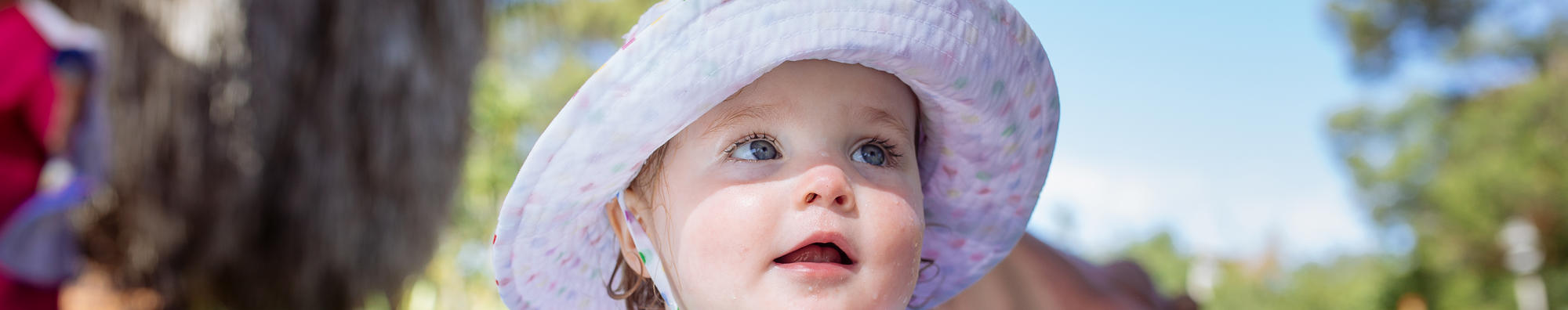 Close-up of young guest at Hippo Beach, wearing a sunhat and looking right of frame.