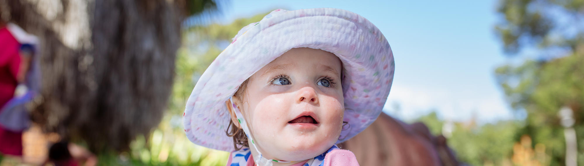 Close-up of young guest at Hippo Beach, wearing a sunhat and looking right of frame.
