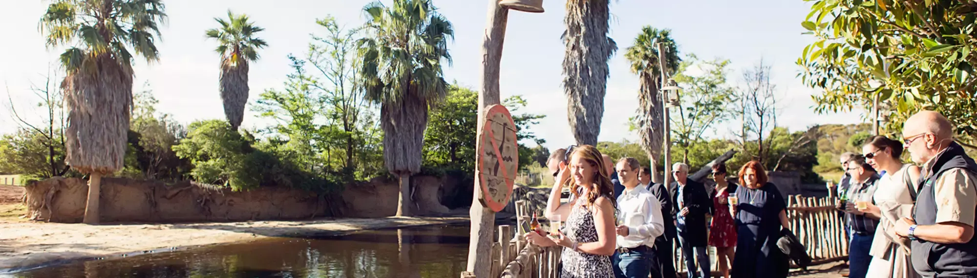 A group of people, on the right, standing on the Boardwalk overlooking the river, to the left.