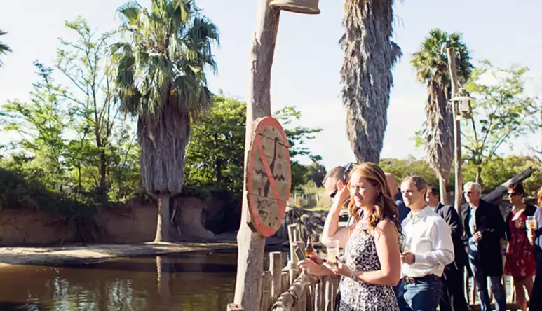 A group of people, on the right, standing on the Boardwalk overlooking the river, to the left.