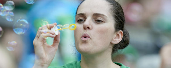A woman blows bubbles while grinning.
