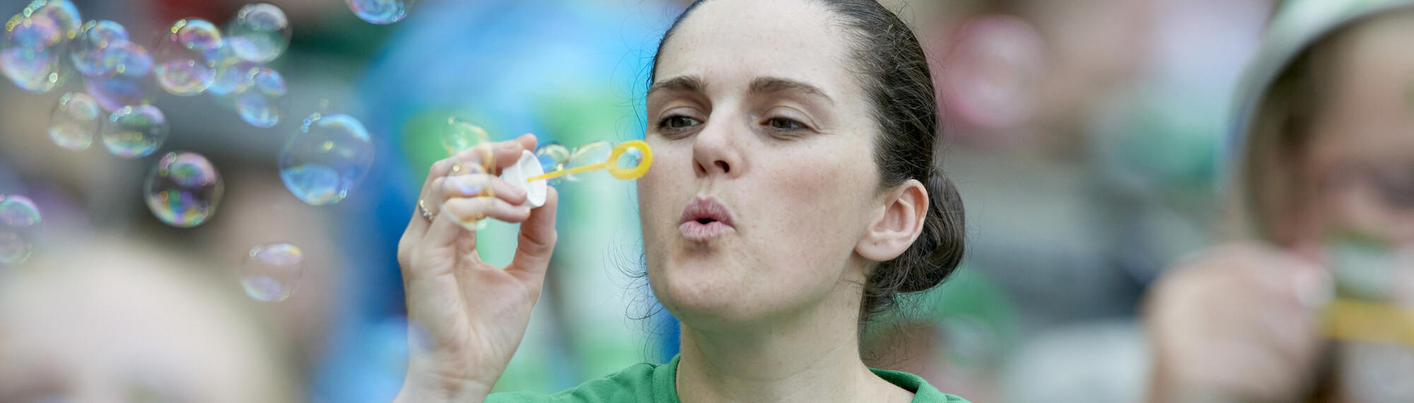 A woman blows bubbles while grinning.