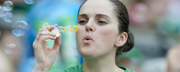 A woman happily blows bubbles.