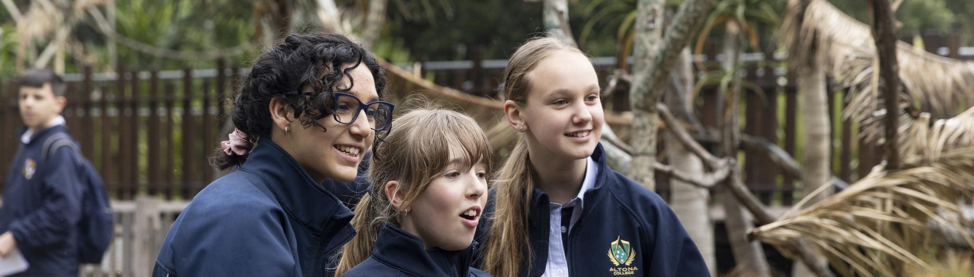 Three students looking enthusiastically off-frame, all facing right.