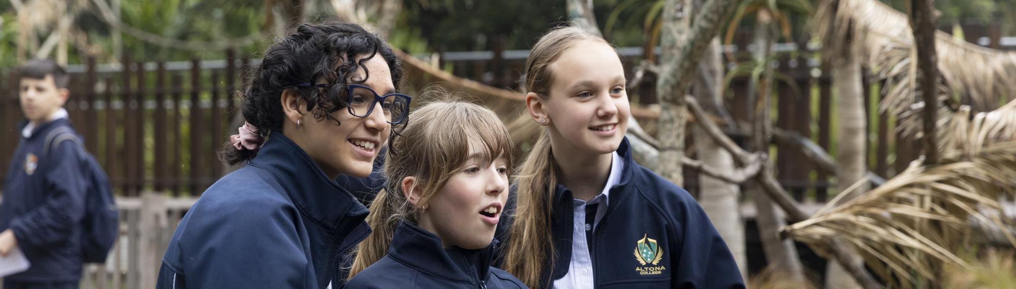 Three students looking enthusiastically off-frame at Lemur Island, all facing right.