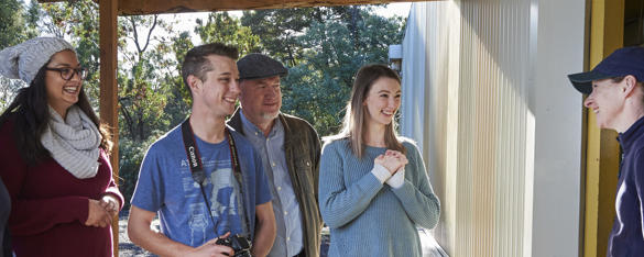 Two Zoo keepers stand with a group of four adults, all grinning.