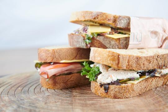 Close up shot of three stacked sandwiches, each with various fillings inside them.