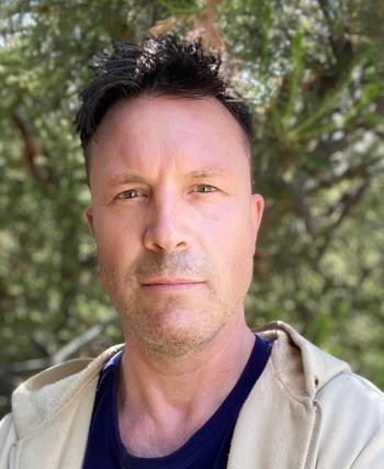 Portrait of Biologist Nick, in front of a leafy backdrop.