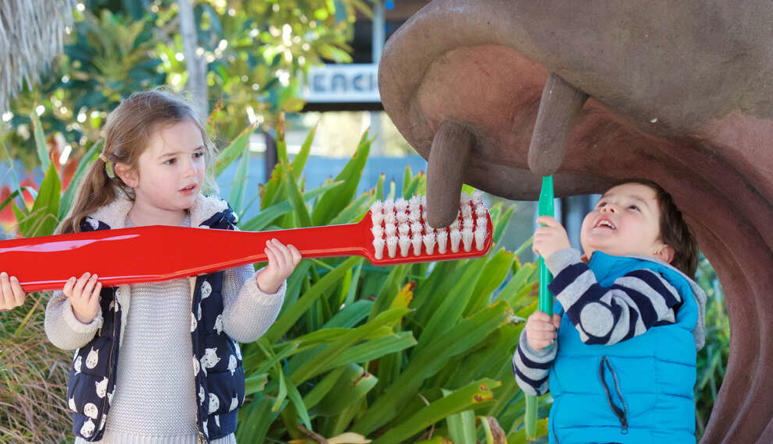 Three children brushing fake hippo's tooth