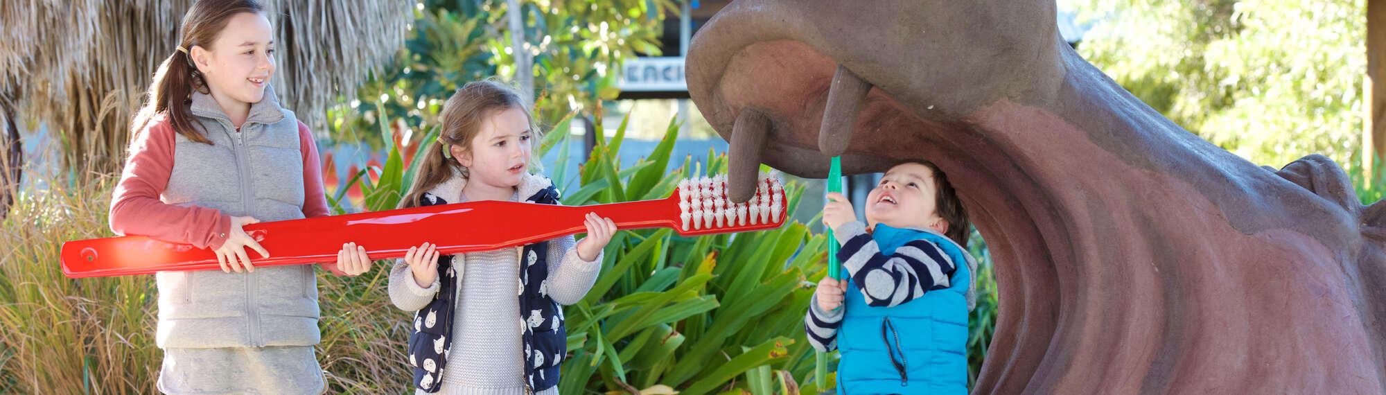 Three children brushing fake hippo's tooth