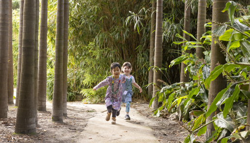 Two children with lanyards running through the bamboo forest