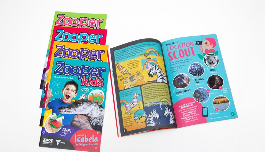 Five Zooper Kids magazines, four in a slanted stack on the left, one open on the right.