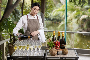 Caterer filling some forty-eight champagne glasses on a tray in the Rainforest Room.