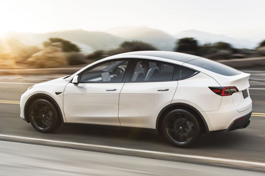 A white hatchback car on the open road, heading left.