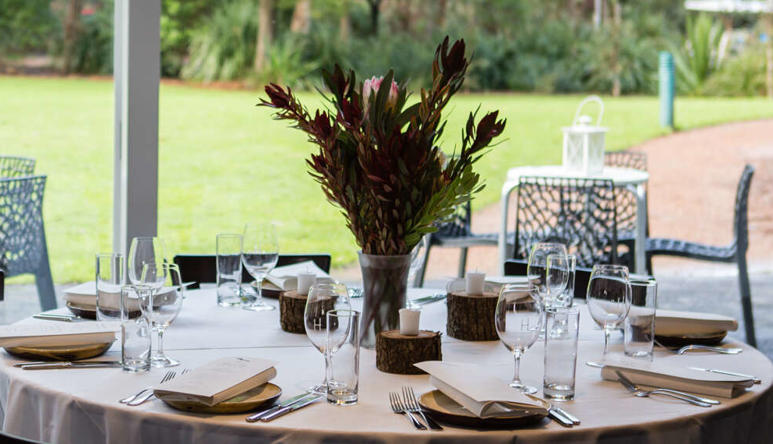 View of Brolga Room, set up for function with one dining table, eight chairs and two outdoor tables with four chairs.