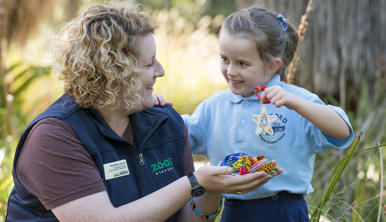 Student with Educator holding up a beads for wildlife craft creation