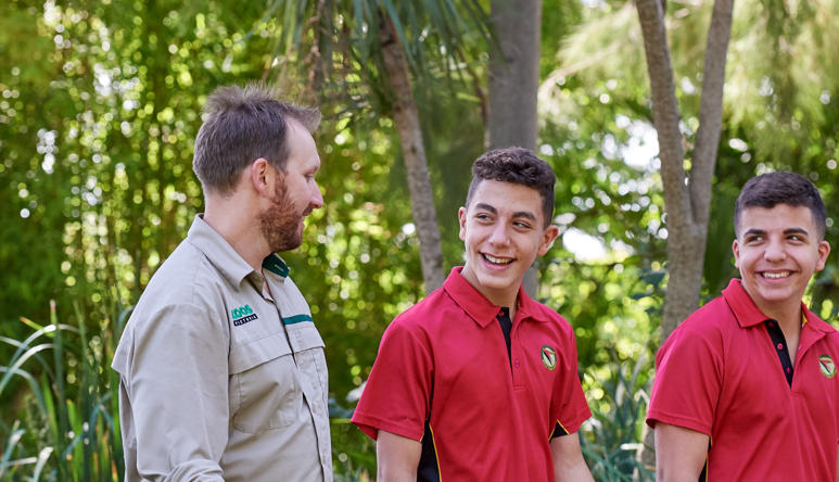 Keeper (in khaki) and two students (in red uniforms) in conversion while walking along the Forest Trail.