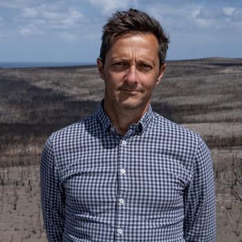 Brendan Whittle, looking at the camera against a hilly field.