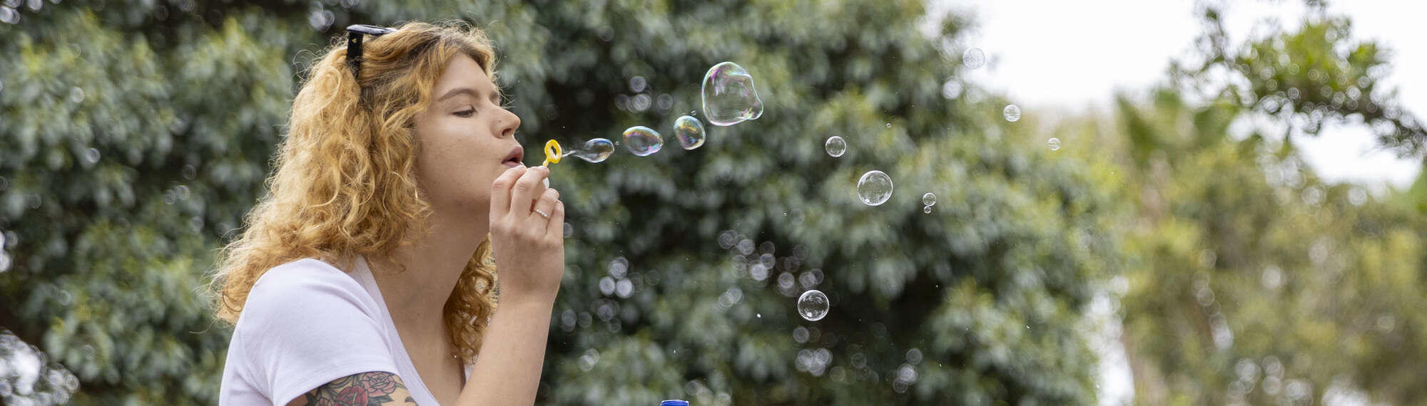 Woman blowing bubbles, facing right.
