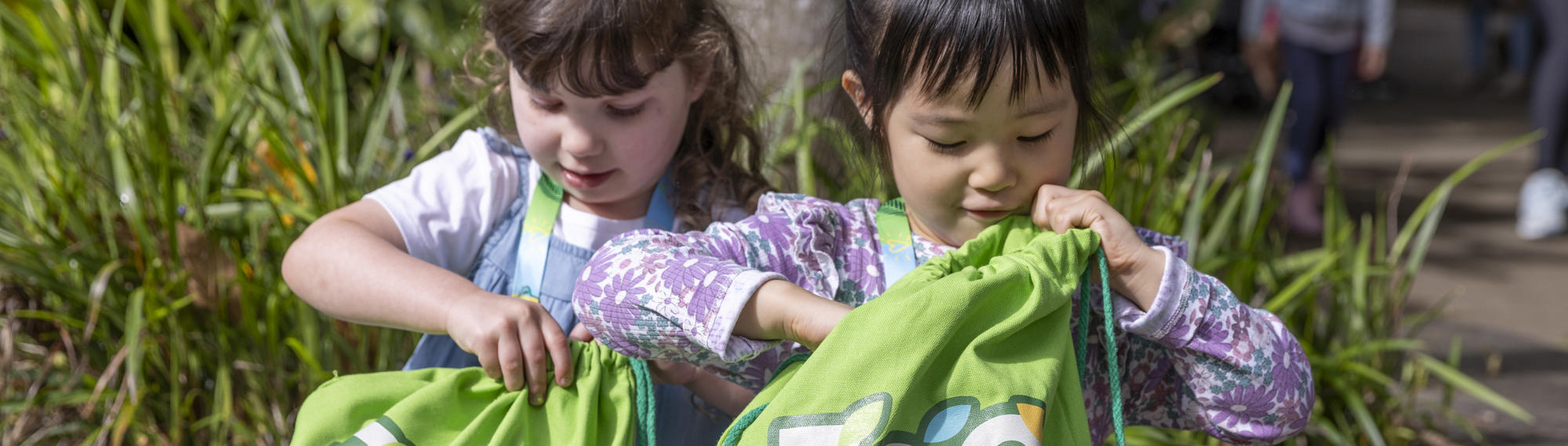 Two young guests searching through green Zoo Crew bags.