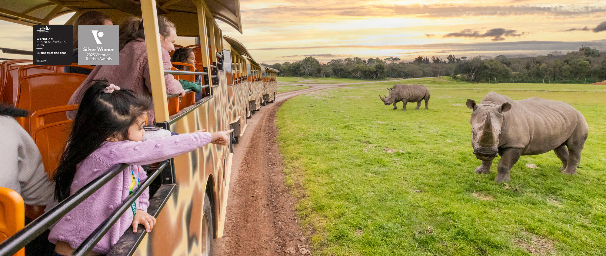 "Wyndham Business Awards... Business of the Year"; "Silver Winner, Two-thousand Twenty-five Victorian Tourism Awards" - At least five guests looking to two Rhinoceroses from their articulated Safari Bus, with one pointing to the Rhinos.
