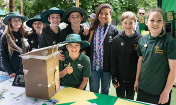 At least eight students, with their teacher, all smiling and posing to the camera behind their Fighting Extinction Schools Showcase project.