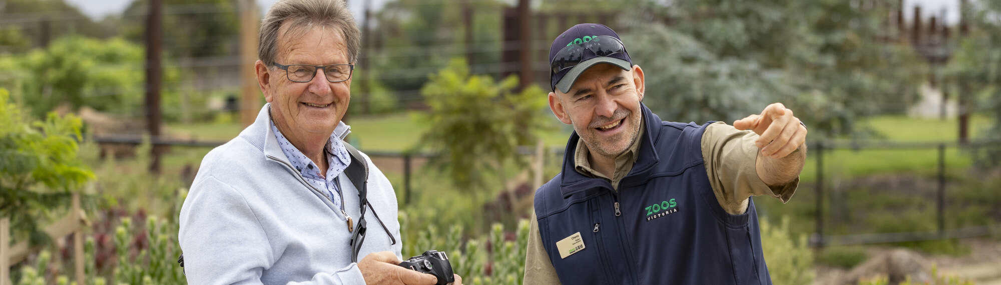 Behind the scenes hosted Elephant Experience. Visitor taking photo of elephant with host pointing out things.