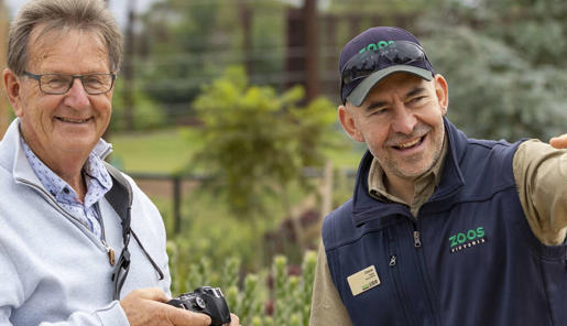 Behind the scenes hosted Elephant Experience. Visitor taking photo of elephant with host pointing out things.