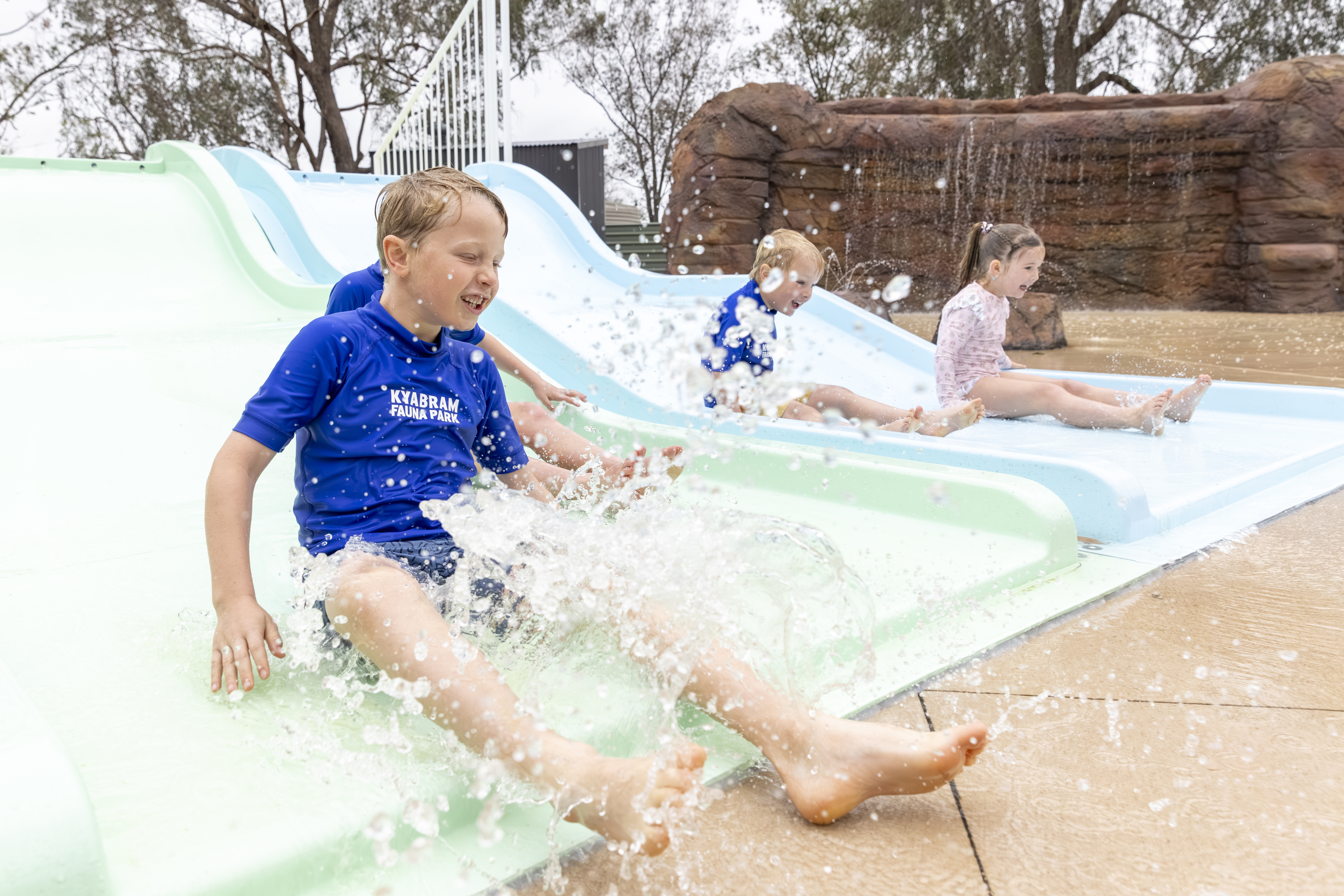 Four young guests enjoying the Splash Park's aqua water slide.