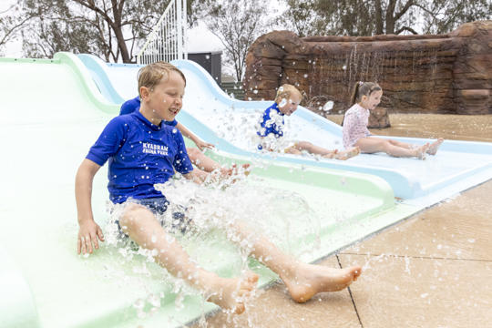 Four young guests enjoying the Splash Park's aqua water slide.