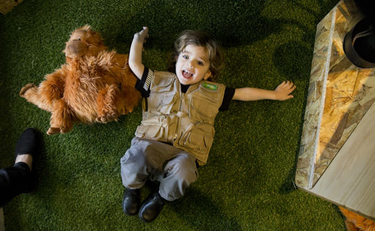 Young guest playfully lying on the floor in Keeper Kids, with a plush Orangutan to the left.