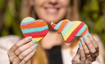 A woman holding out a heart-shaped and an elephant shaped cookies.