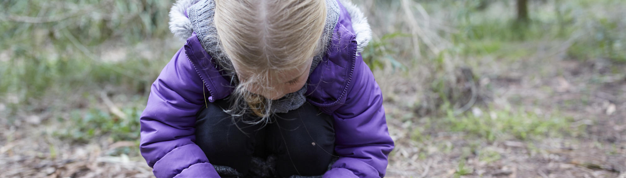 A young guest crouched down and picking up feathers from the ground.