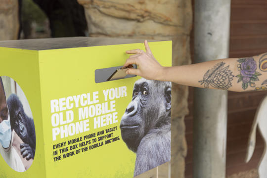 "Recycle your old mobile phone here"; an arm is ready to drop a gold phone into the Bin for "They're Calling On You."