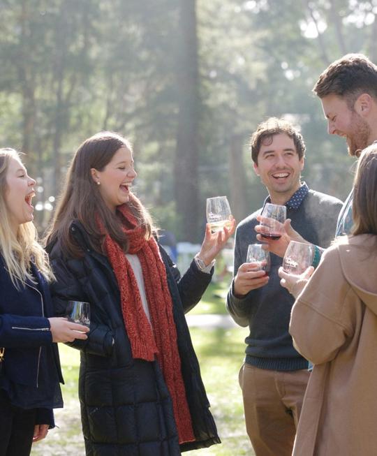 A group of young adults holding wine glasses, smiling