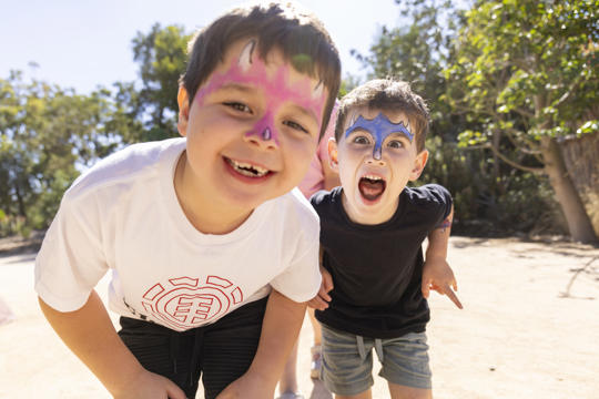 Kids posing for the camera with their faces painted.