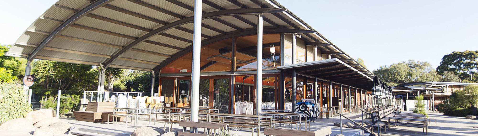 View of the Meerkat Bistro with a curved roof, and picnic benches out the front.