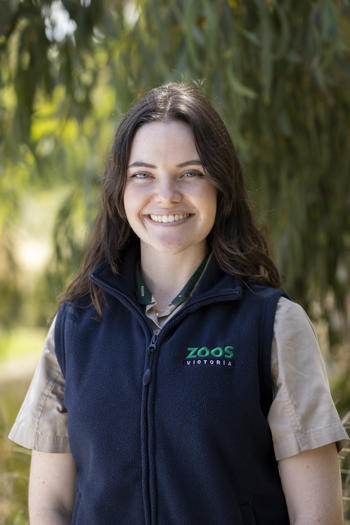 Portrait of Intern Angie, in front of a leafy backdrop.