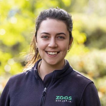 Detection Dog Officer La Toya, smiling to the camera in front of a leafy backdrop.