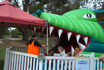Five young guests lining up for entering the Inflatable Monster Crocodile at Wild Weekender, accompanied by a Supervisor.