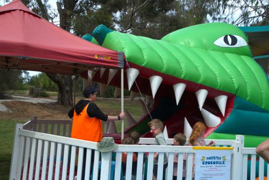 Five young guests lining up for entering the Inflatable Monster Crocodile at Wild Weekender, accompanied by a Supervisor.