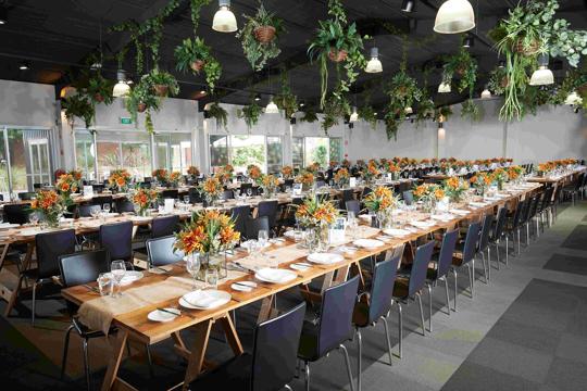 View of the Leopard Lodge, prepped for a ceremony with flowers, hanging plants, rowed tables and chairs.