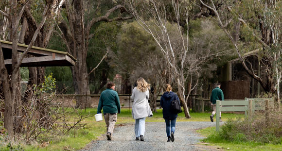 Two guests walking with a Keeper along the trail at Kyabram Fauna Park.