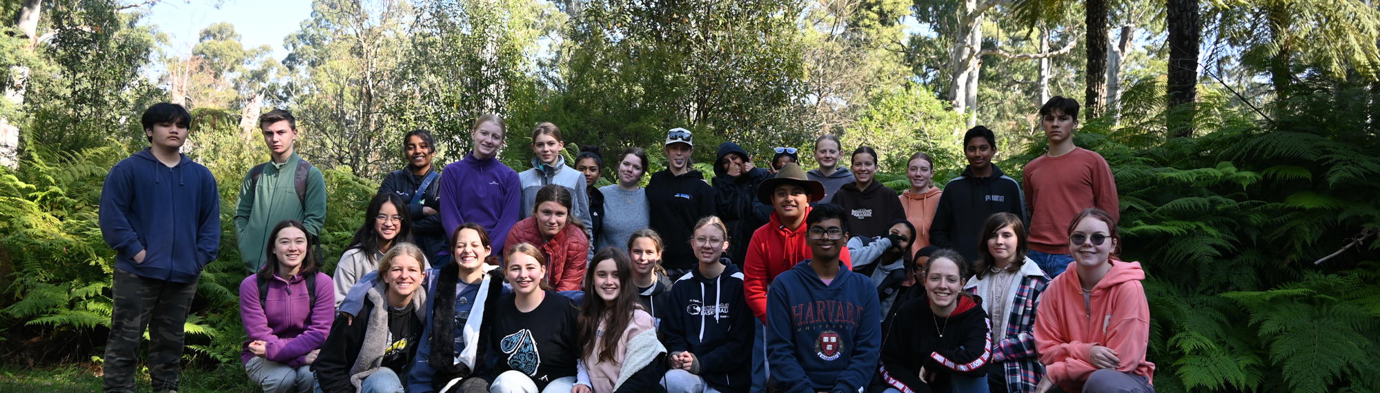 Thirty-two students (youth conservation leaders) posing for the camera, against a leafy backdrop.