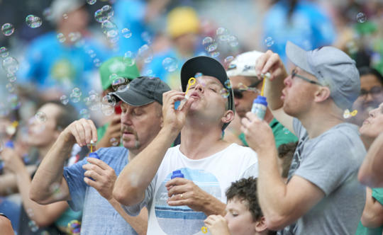 People blowing bubbles at the Melbourne Cricket Ground as part of a world record attempt to raise awareness of blowing bubbles, not balloons.