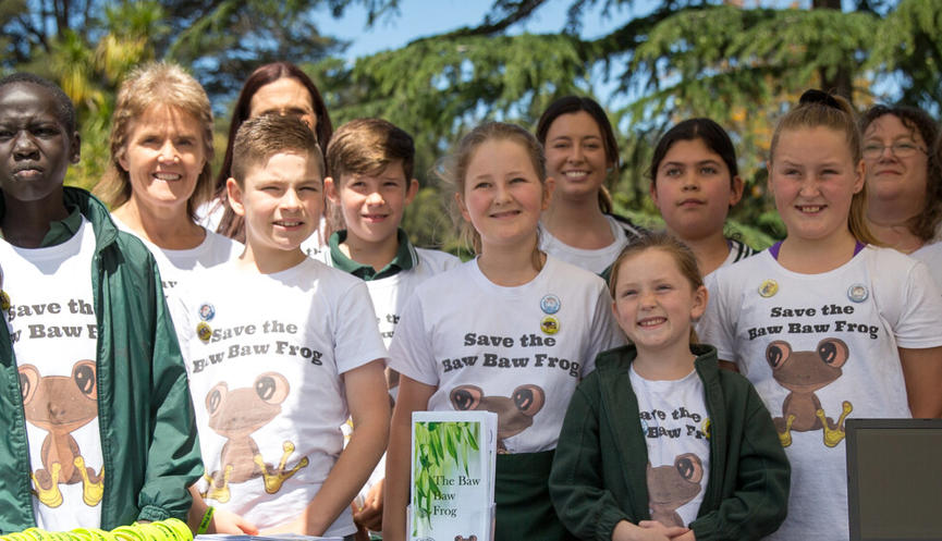 Group of students standing in a row smiling wearing shirts saying 'save the Baw Baw' frog