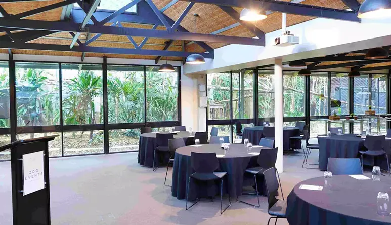 A wide-shot of the Bong Su Room, with the lectern and six tables with chairs surrounding them.