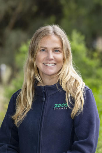 Portrait of Dr. Sally, smiling to the camera against a leafy background.